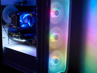 The computer's system block. Components of a gaming PC with RGB illumination. Cooling fan with backlight in the computer system unit. The concept of eSports and gaming © Om.Nom.Nom