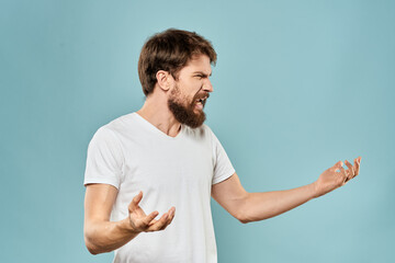 Man gestures with his hands emotions displeasure white t-shirt blue background