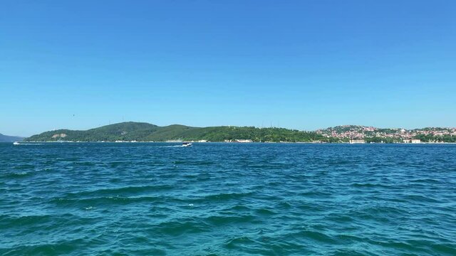 Footage of boats passing on Bosphorus strait in Tarabya area of Istanbul. Kanlica / Beykoz area of Asian side is in the view. It is a sunny summer day. Camera pans left.