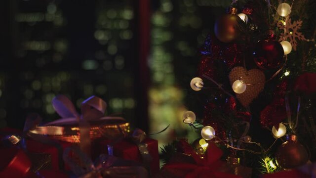 New Years Christmas background. Christmas tree. The candle is flashing. Decorations, red gold balls and glowing bulbs on the tree. Warm home mood. Depth of field, soft focus. Red camera 4K
