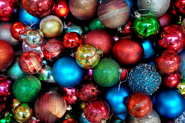 Fototapeta na wymiar Top view of pile of dark and colorful Christmas balls for an abstract holiday season background backdrop pattern. 
