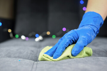 Hand in protective glove cleaning sofa with rag. christmas cleaning or clean up. Maid cleans furniture in a house. 