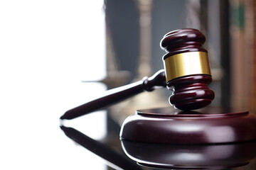 Law theme. Judge chamber. Judge’s gavel and collection of legal books on the brown desk and the brown background.