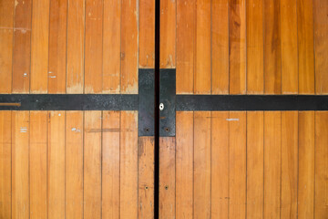 Closeup of wooden door with two crossed black strip.