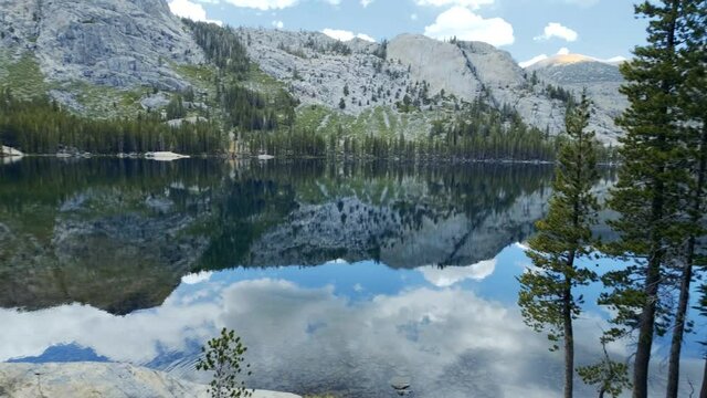 Beautiful clear lake in the Sierras reflection of trees and mountain (pan shot, 60 fps slowed to 30 fps)