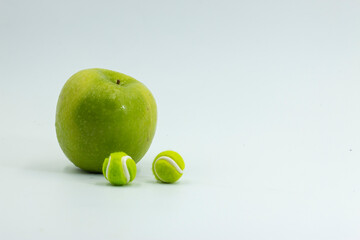 Tennis ball with apple are on green grass