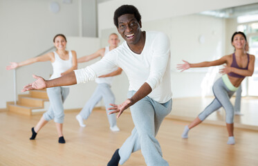 Fototapeta na wymiar Positive aframerican man enjoying active dances in modern dance studio.