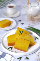 Bika Ambon, Indonesian honeycomb cake with square slices in white plate.
It is made of flour, tapioca, coconut cream, lime leaf, and sugar. Selective focus.
