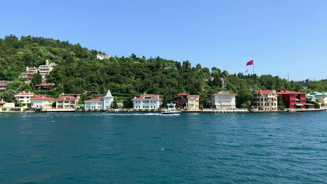 Footage of yacht passing in Anadolu hisari / Kandilli area of Istanbul on Bosphorus strait. Beautiful scene. It is a sunny summer day. Camera moves forward.