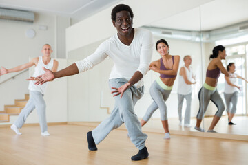 Fototapeta na wymiar Adult people learning swing steps at dance class and smiling
