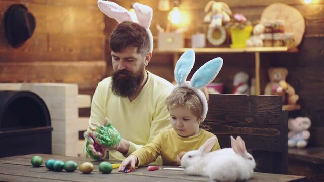 Father and son painting eggs for easter. Family play with easter bunny rabbit.