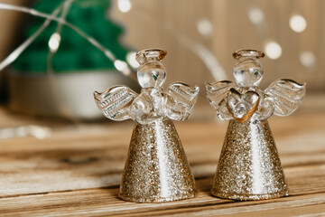 Christmas card with angels, fir tree and garland on wooden background. Defocused lights background. Selective focus.
