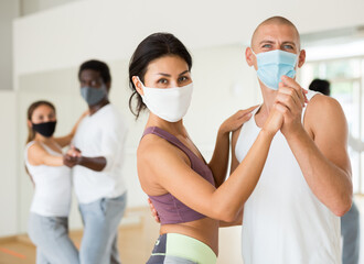 People in protective masks learning swing steps at class