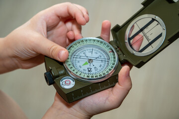 Children's hands holding a compass. A little boy holds a green compass in his hands. Learn orienteering. Childhood curiosity and adventure