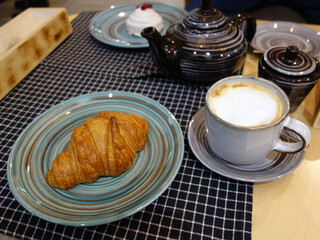 Breakfast in the cafe. Breakfast for two person with cup of coffee and fresh croissant, a pot of tea and cake. Top view.       