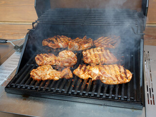 Delicious grilled meat on outdoor barbecue grill with smoke. 