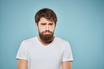 Obraz premium Man in white t-shirt lifestyle studio emotions facial expression blue isolated background