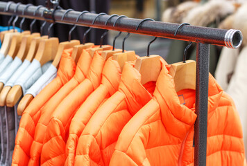 Winter orange jackets on hanger in the store close-up © TATIANA KIM