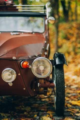 Abwaschbare Fototapete Braun Vertikale selektive Fokusaufnahme eines Oldtimers in einem Herbstpark