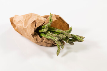 Select focus of a handful of wild asparagus wrapped in brown paper bag. vegan food concept.