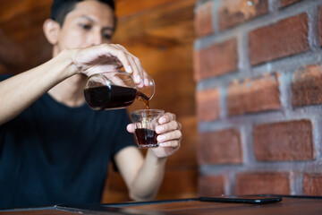 closeup male pour coffee into a cup in a cafe