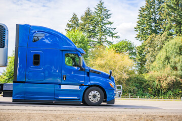 Blue big rig industrial grade semi truck with grille guard and refrigerator unit on the semi...