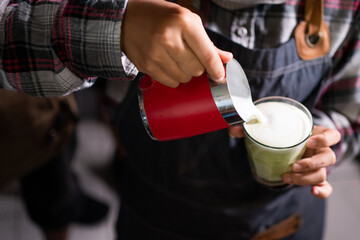 Fototapeta na wymiar closeup barista pour milk into a cup in a cafe making latte art