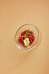 Tomatoes with stracciatella in round transparent glass bowl