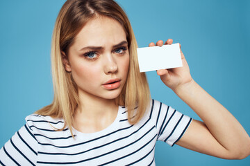 Woman with a business card in her hands a striped T-shirt blue background Copy Space