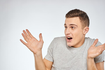 Cheerful emotional man gray t-shirt gesturing with hands studio lifestyle