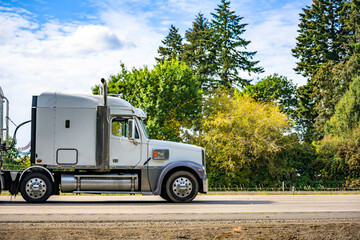 Profile of industrial big rig semi truck tractor with semi trailer driving on the flat highway road...