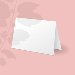 White standing greeting card mockup template with holly berry branch with leaves overlay shadow.