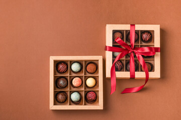 Chocolate sweets from various chocolate in a box a satin ribbon brown background