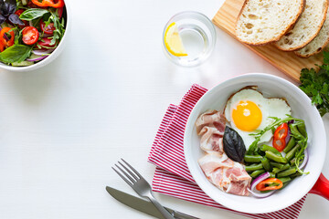 European breakfast: heart shaped egg, bacon, green beans on a white table. Selective focus. View from above. Copy space