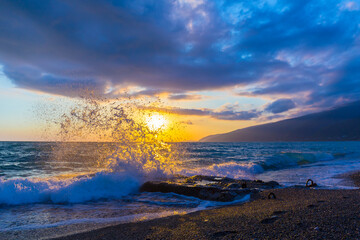 Beautiful shoreline scene with waves at sunset beams