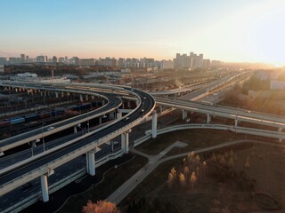 Fototapeta premium Aerial view panorama of multi-level transport interchange in the center of the big city at dawn. Beautiful panoramic landscape infrastructure of modern city from great height