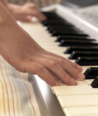 Fototapeta premium The hands of caucasian unrecognizable boy are learning to play synthesizer.