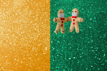 Selected focus of Gingerbread men in a protective masks are levitating  on the bokeh green and gold background. The concept of creative art Christmas, Color Trends.