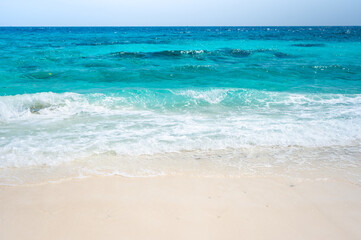 Clear sea waves and white sandy beach in summer.