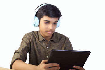 Indian young boy using digital tablet while attending the online classes at home	
