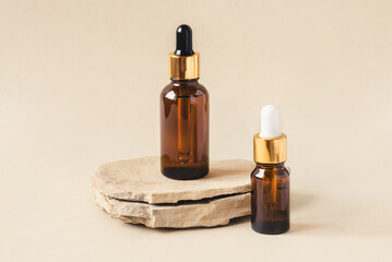 Two brown bottles of cosmetics on a natural beige background. Stone podium. Front view.
