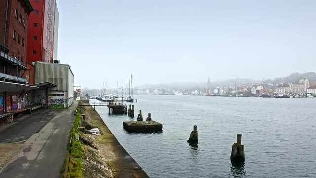 Drone flight over foggy Flensburg port and the small town overview, Germany