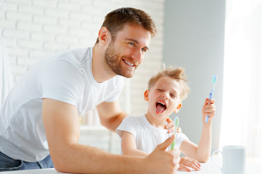 Dad and little son brushing teeth together