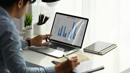 A businessman is using laptop  analyzing market data information at modern office.