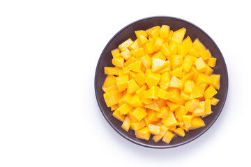 Diced mango in a black plate on white background. Top view.