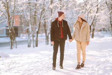 Happy Couple in love walking and having fun in snow forest. Young man and woman playing in the snow on winter holidays. Christmas, New year. Winter lifestyle.