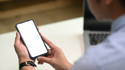 Closeup of man hand using cell phone with blank screen on working space. Blank screen for graphics display montage.