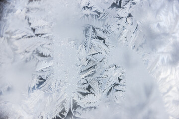 Texture of blue frost on a glass window. Frosty cold weather. White ice patterns texture close-up. New year and Christmas background