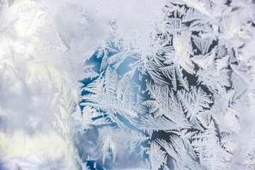 Texture of blue hoarfrost on a glass window. Frosty cold weather. White ice patterns texture close-up. Winter New year and Christmas background