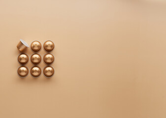 Caffeine, hot drinks and objects concept - close up of golden capsules or pods for coffee mashine on beige background. Top view with space for text. Flat lay..